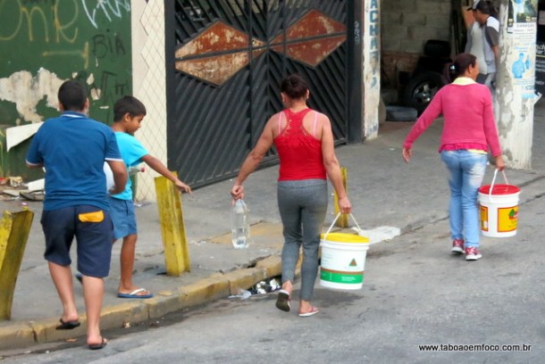 Mulheres carregam baldes de agua em Taboao