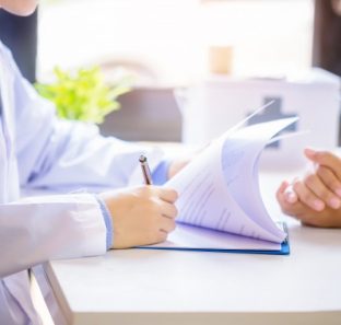 paciente-de-consulta-do-homem-do-doutor-ao-encher-acima-um-formulario-de-candidatura-na-mesa-no-hospital_1150-12966